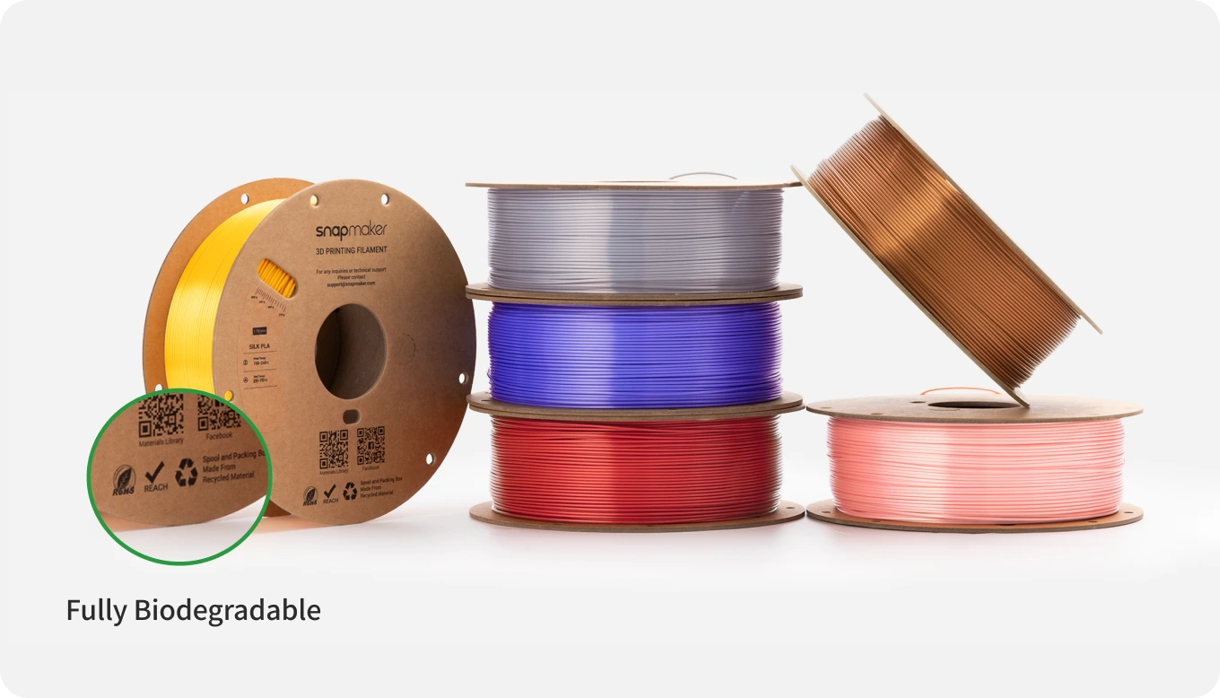 Colorful spools of biodegradable filament stacked on a neutral background.