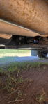 HornBlasters air compressor and tank mounted on plate under rusted exhaust on vehicle chassis