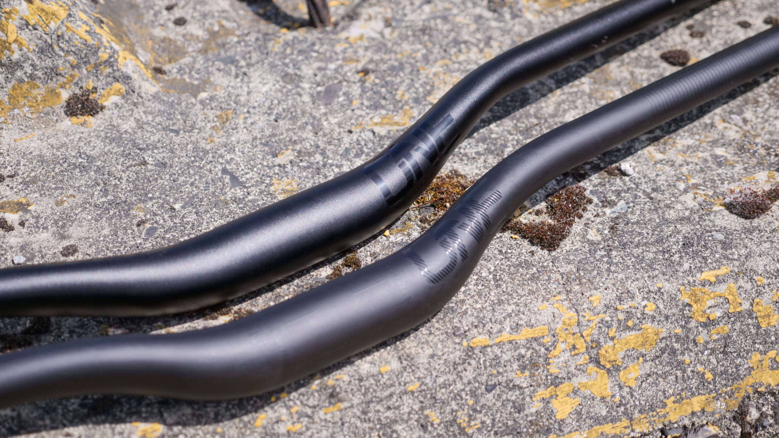 detail of oval oneup components carbon and aluminum mountain bike handlebars on the concrete