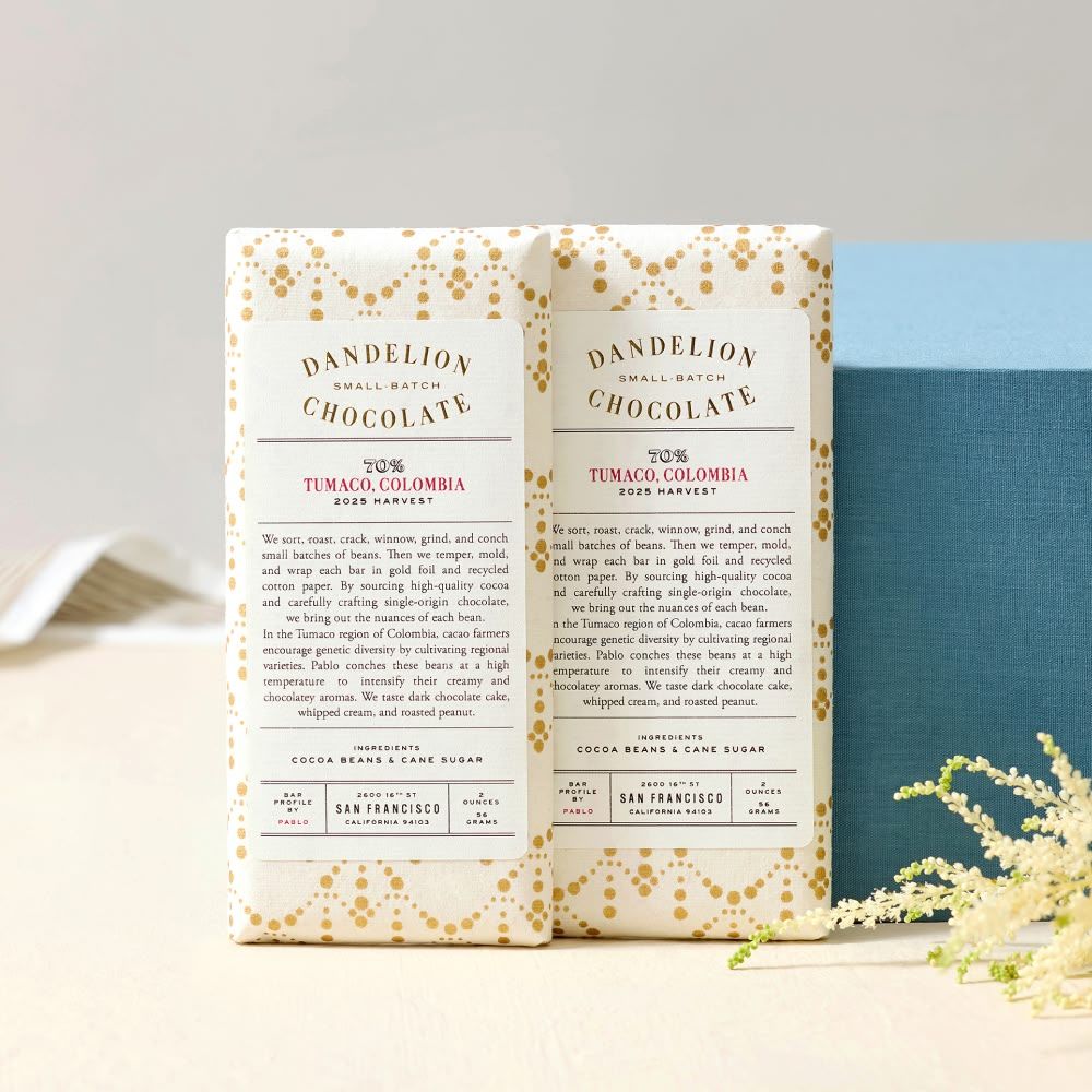 Two chocolate bars with decorative packaging and text, beside a blue box.
