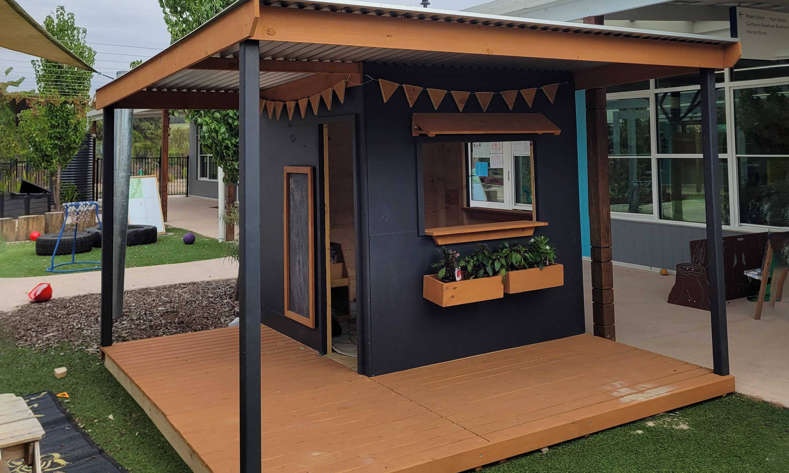 A painted wraparound verandah cubby house with a flat roof