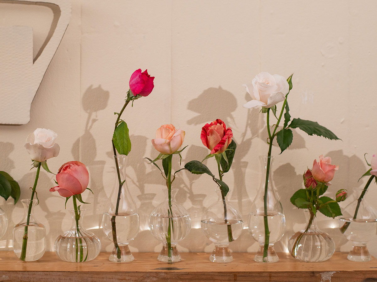 A variety of roses displayed in glass vases on a wooden table.