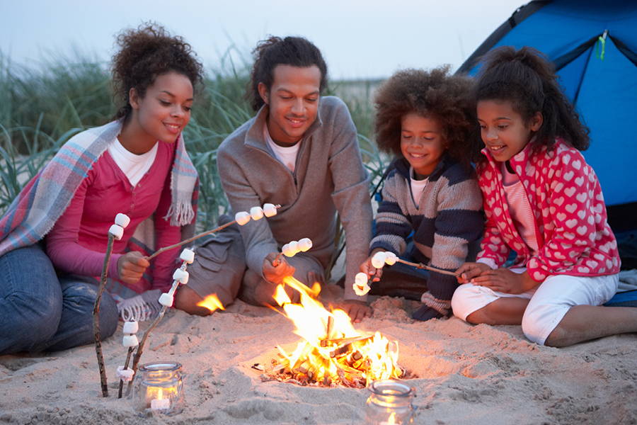 family roasting marshmallows on campfire on beach