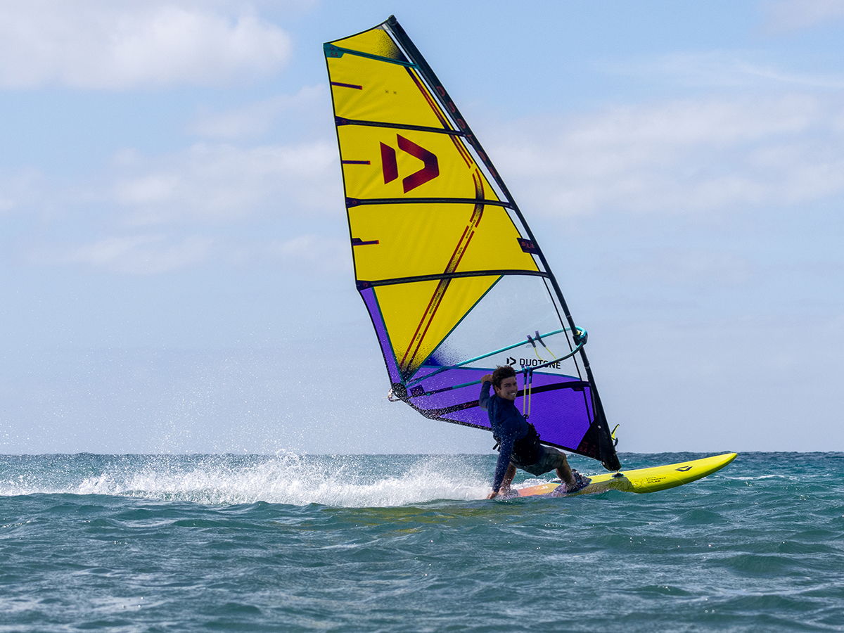 A person windsurfing on the ocean with colorful sails.