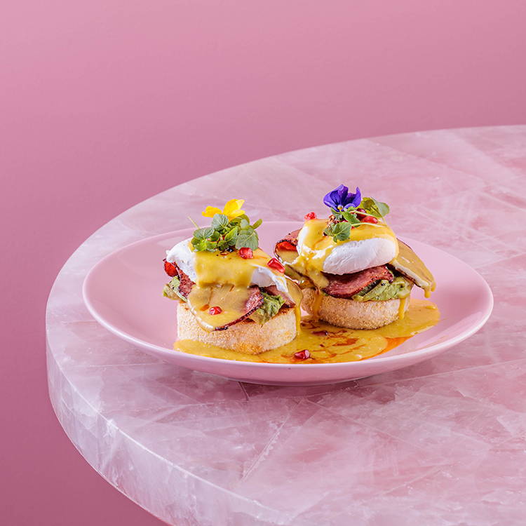 Eggs benedict with flowers on a pink plate