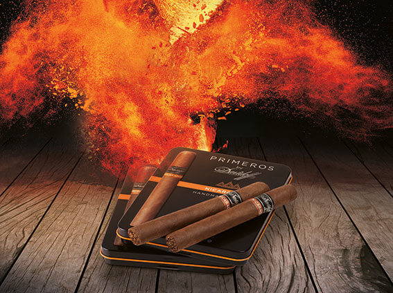 Two Davidoff Nicaragua Primeros lying on their tin with fire in the background. 