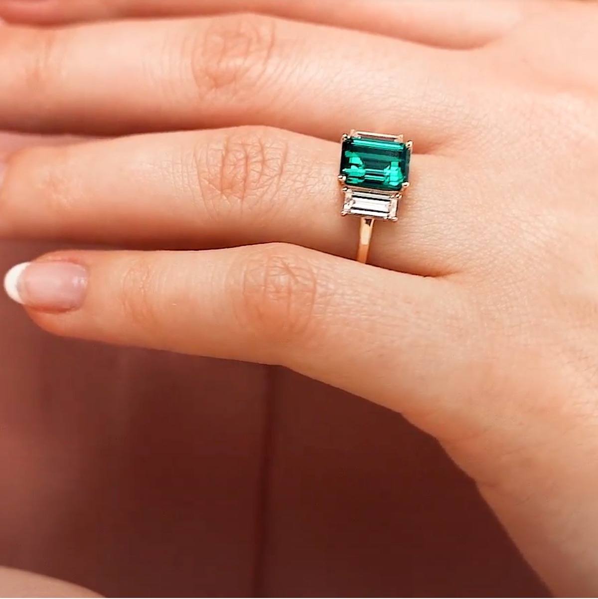 Three stone fashion ring with 2ct emerald cut emerald between two lab grown diamonds in 16k yellow gold