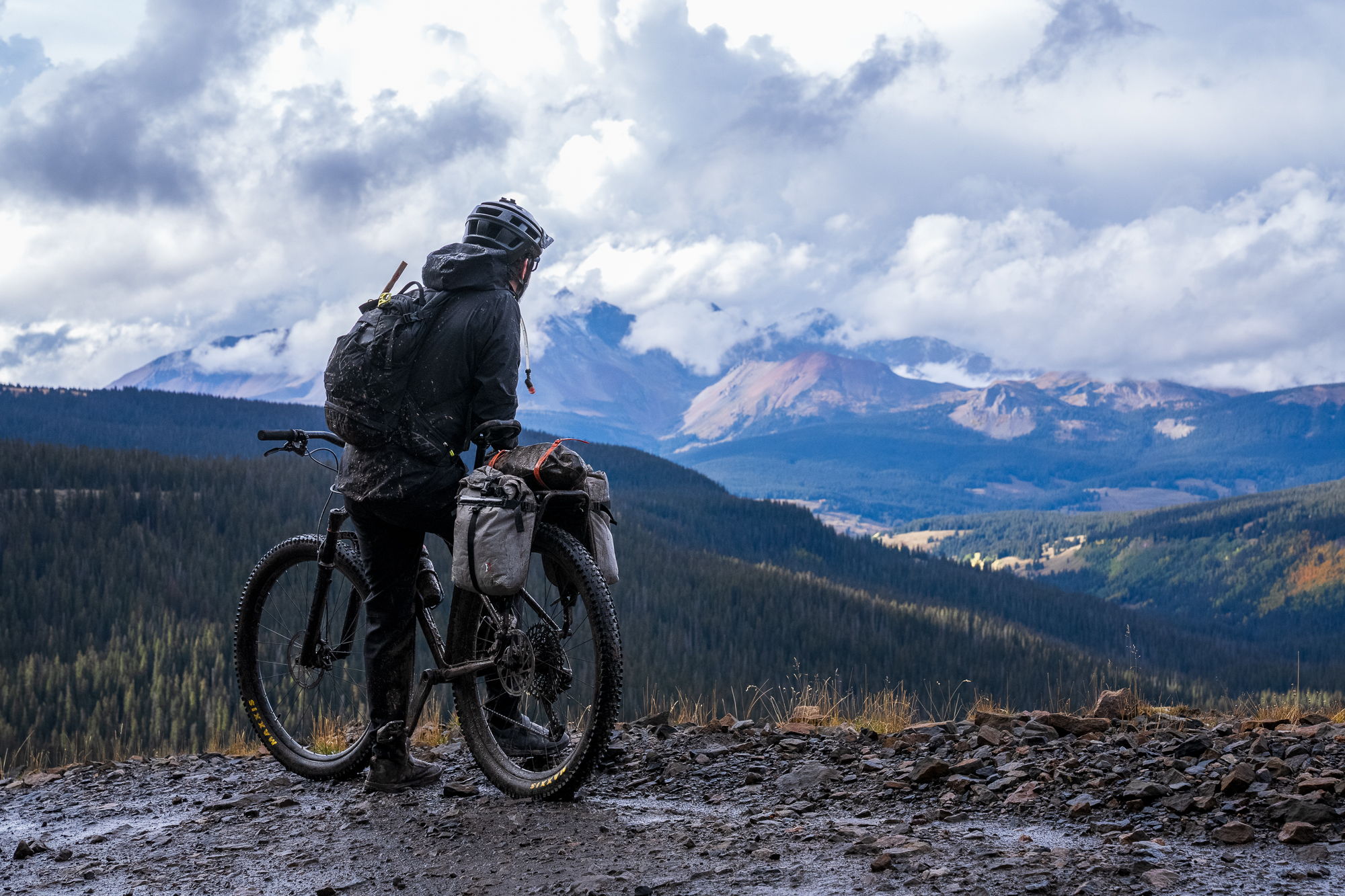 A person on a mountain bike overlooking a scenic landscape with mountains.