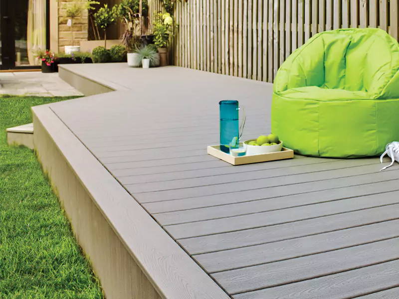 An image of composite decking and a green lounge chair which has been installed in someone's garden. 