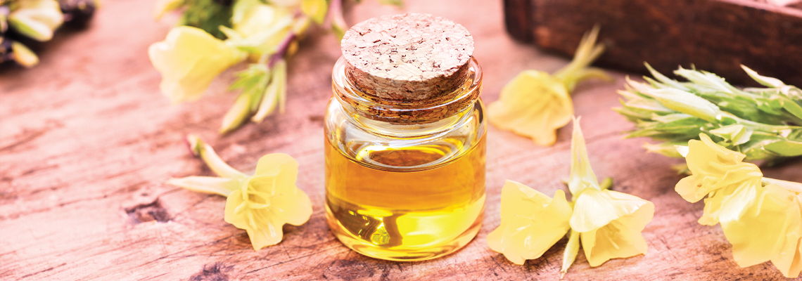 A small glass jar of oil surrounded by yellow flowers.