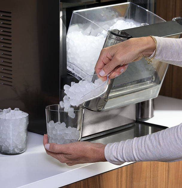 Woman scooping a glass full of Opal Nugget ice at the counter.