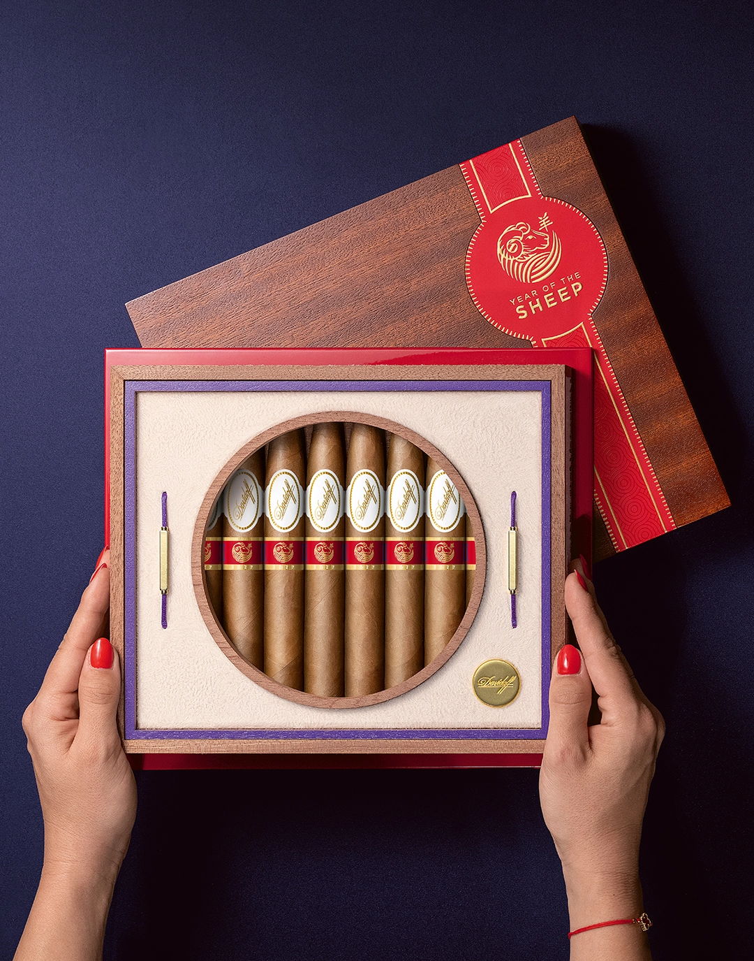  Zwei Hände mit rot lackierten Fingernägeln, die die geöffnete Kiste der Year of the Sheep Limited Edition halten.