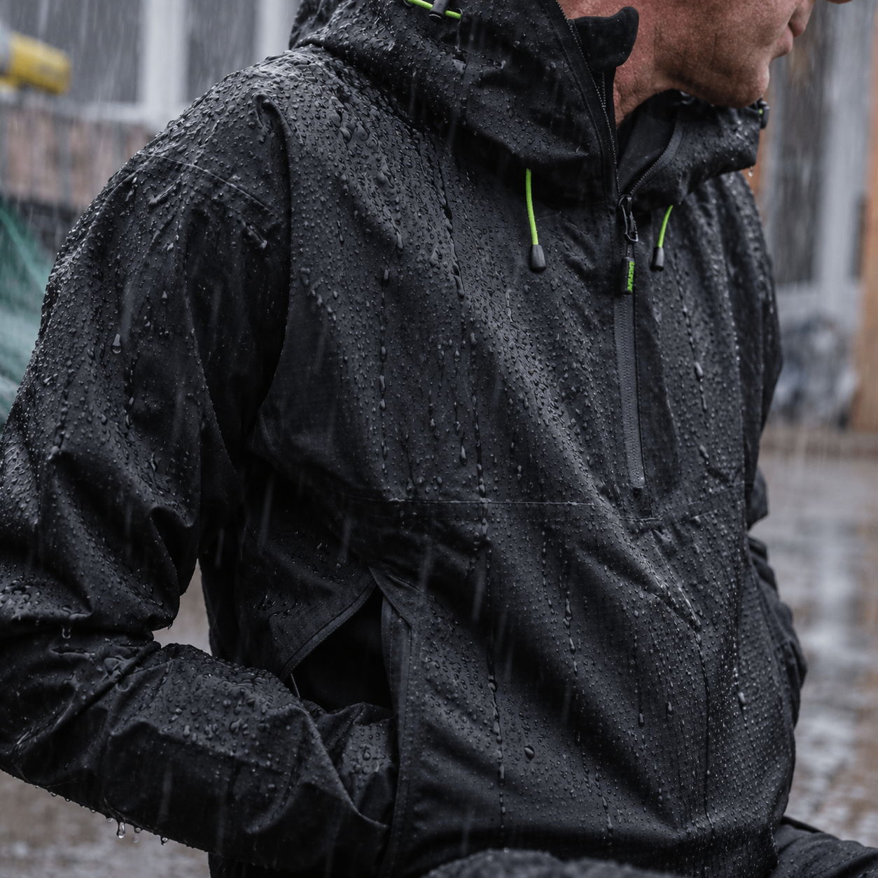 Person wearing a black rain jacket in a wet environment.