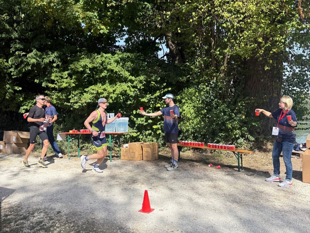 Athleten werden auf der Laufstrecke mit Getränken und Schwämmen versorgt.