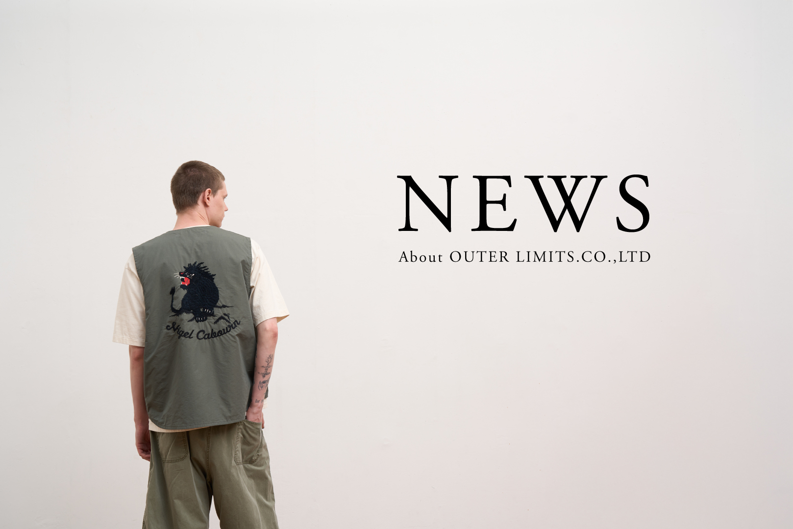 Person wearing a vest with a graphic, standing against a plain wall.