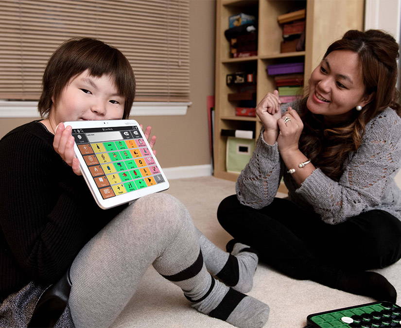 Young girl using a Tobii Dynavox AAC device to communicate with her mother