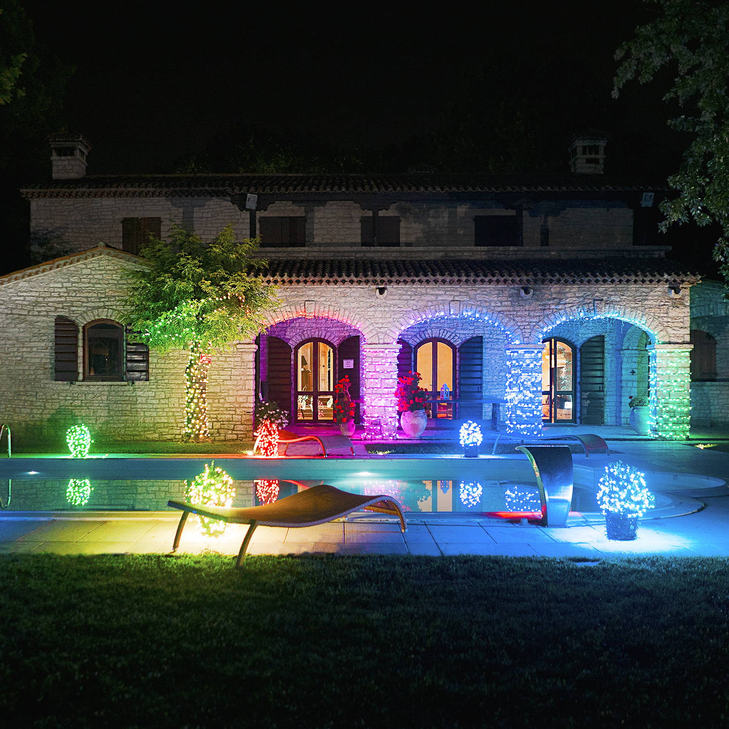 Twinkly lights decorating an outdoor pool area with several colours.