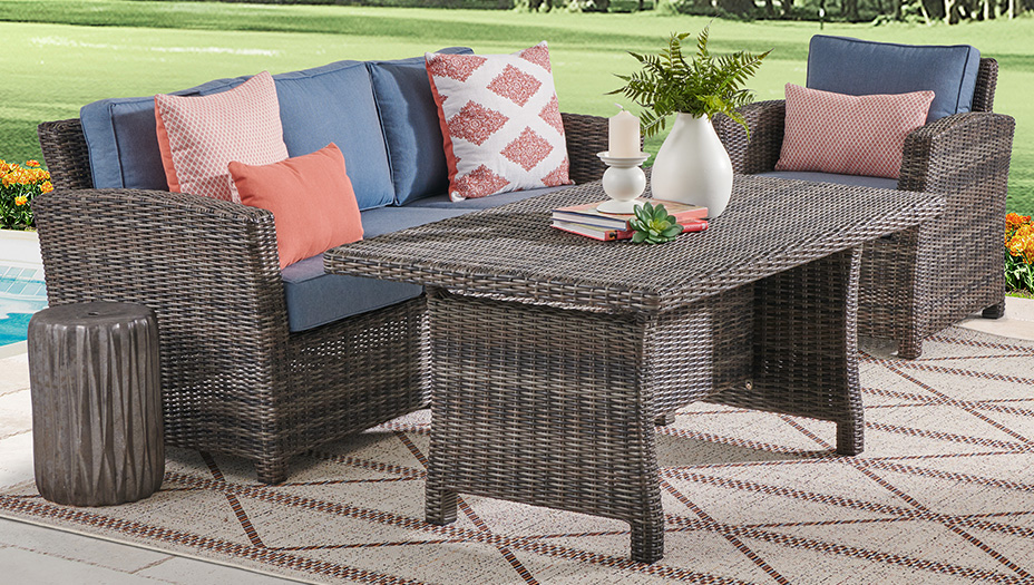 Outdoor seating area with a table, cushions, and decorative plants.
