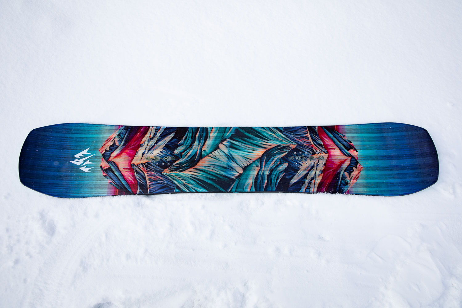 Snowboard with colorful design on a snowy surface.