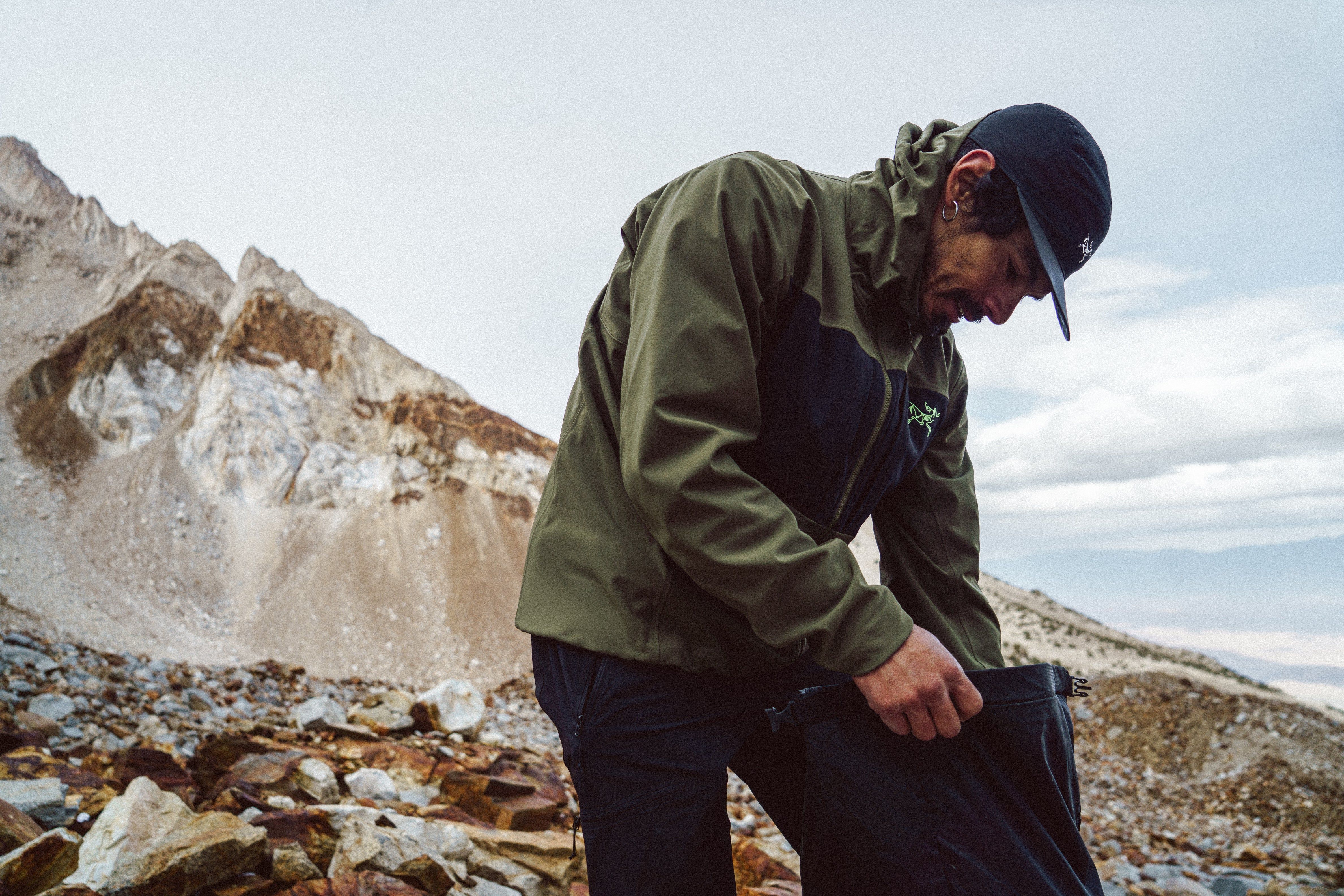 Person adjusting their gear in a mountainous outdoor setting.