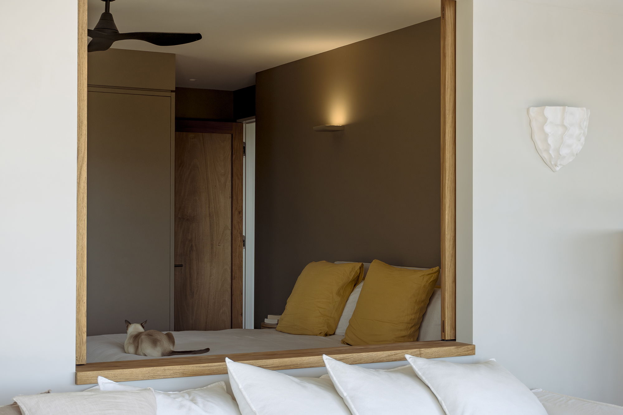 Modern bedroom with yellow pillows and a stylish wall mirror.