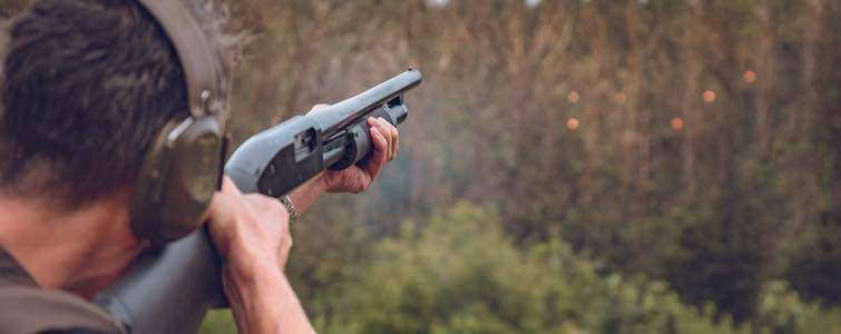 Man Shooting Skeet in a Field With a Shotgun