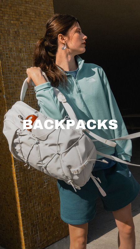 A woman in a teal outfit carrying a backpack.