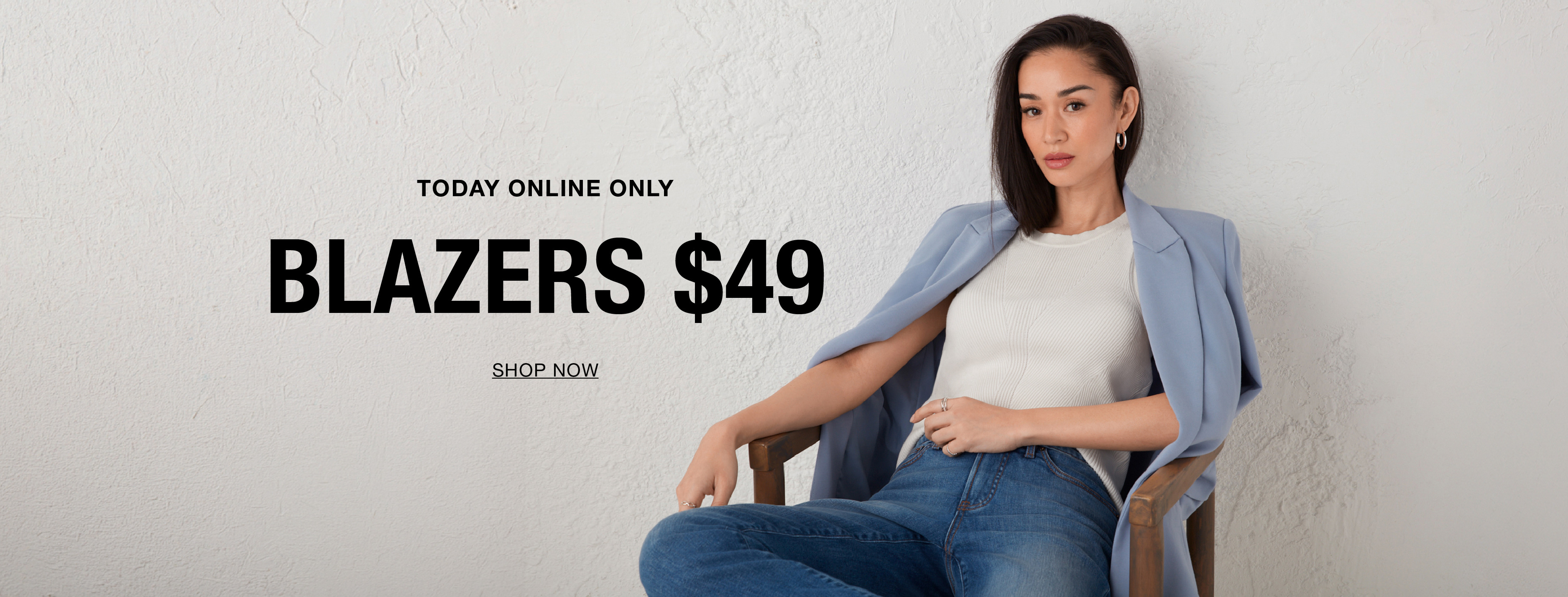 Woman sitting in a chair, promoting blazers priced at $49.