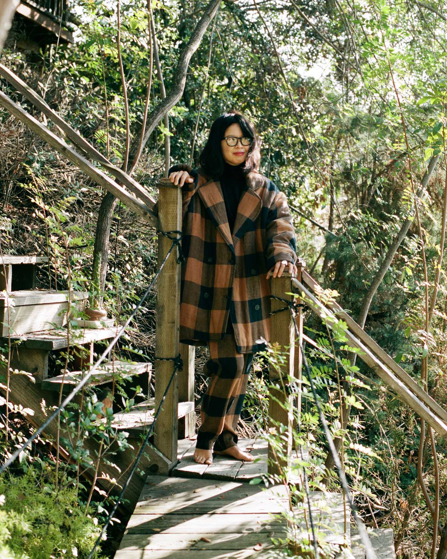 Raina Lee wearing a checked Mara Hoffman suit among trees.