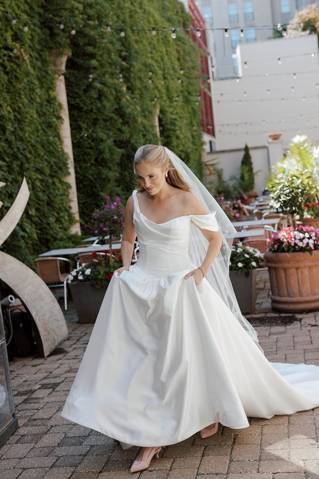 Bride in a white gown walking in a garden setting.