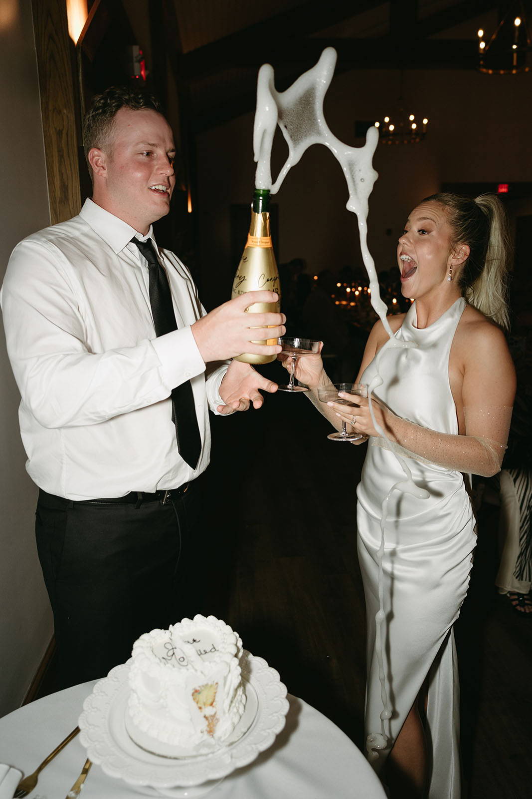 Joyful bride and groom sharing a delightful moment, bursting into laughter as the groom pops open a champagne bottle