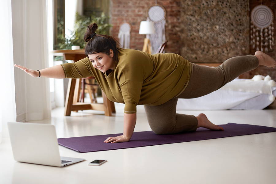 woman doing yoga streaming from her laptop