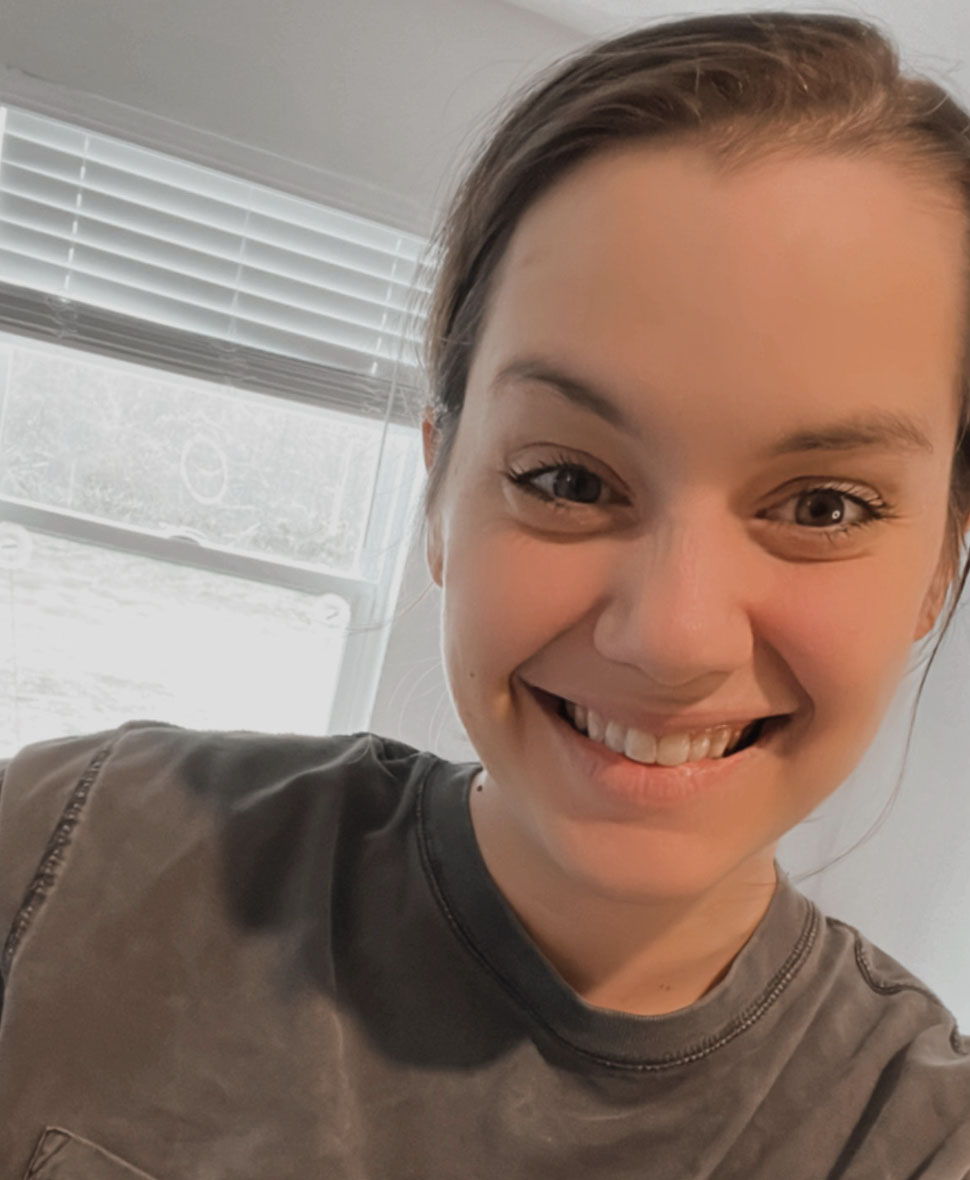 Smiling person in a casual shirt, with a window in the background.