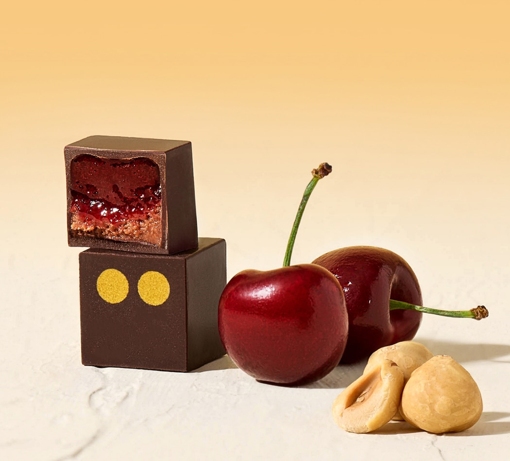 Chocolate cubes, cherries, and hazelnuts on a light background.