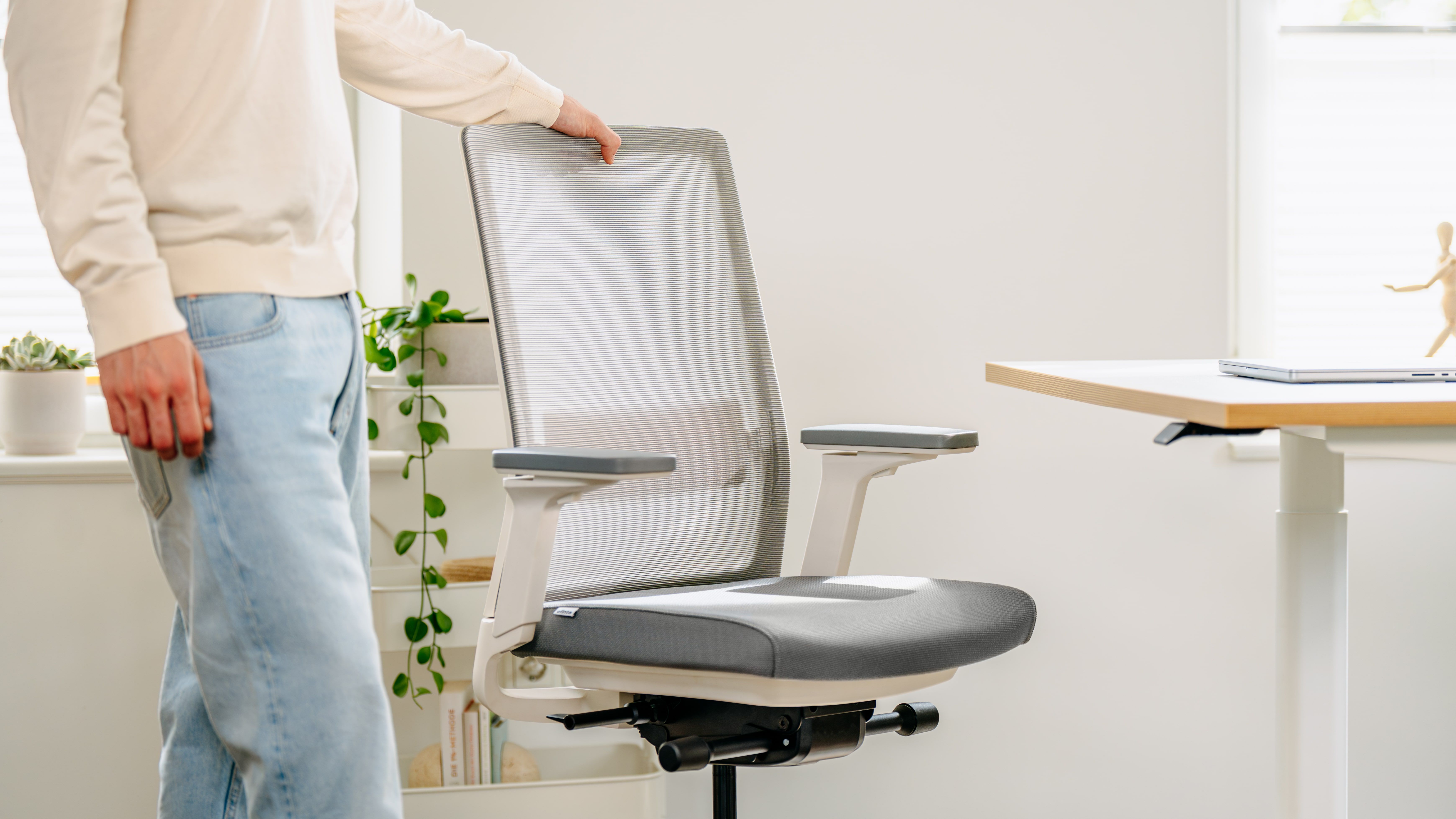 Une personne en train de régler un siège de bureau ergonomique dans un espace de travail lumineux.