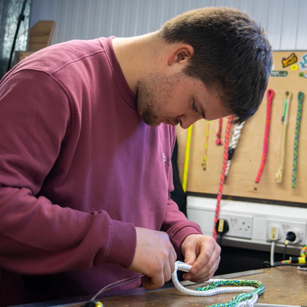 Person working with ropes at a workshop, focused on a task.