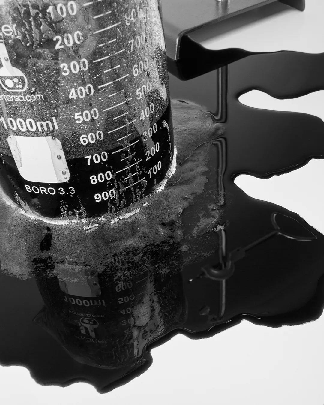 A beaker spilling dark liquid onto a surface.