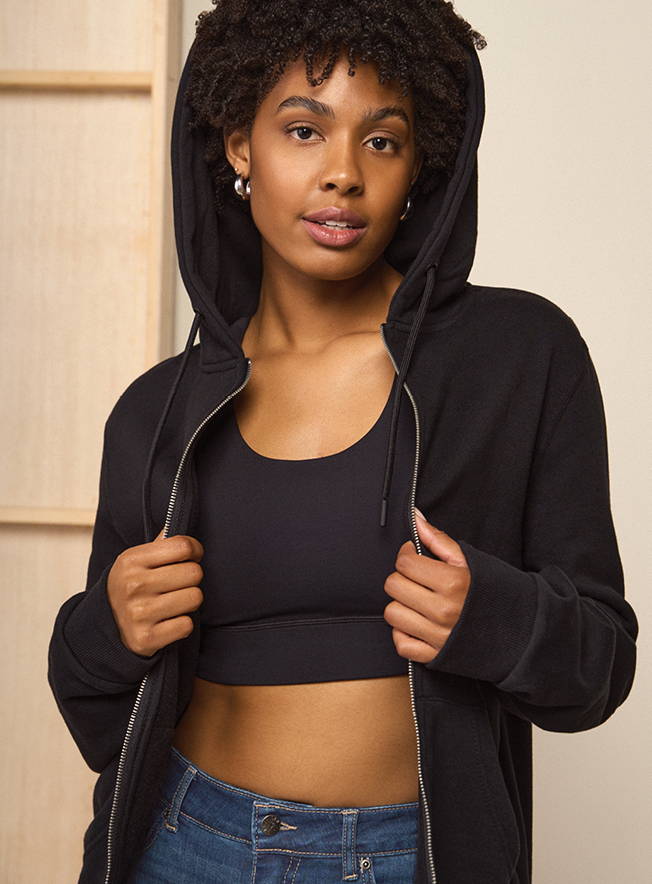 Tall woman wearing a black hoodie and sports bra