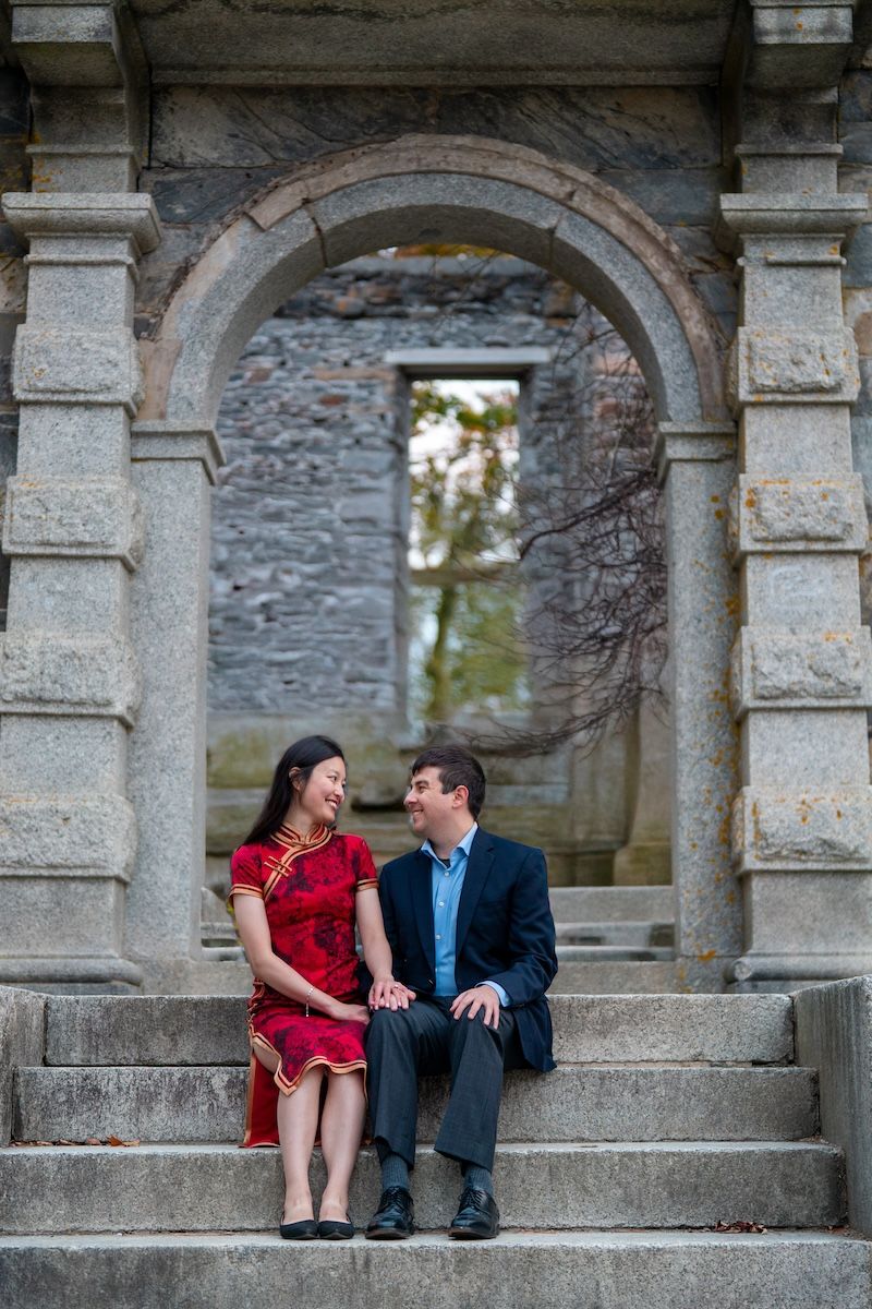 engaged couple posed on stairway in front of arch