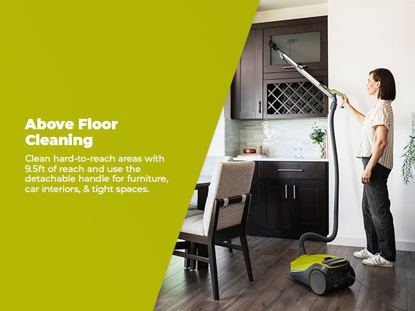Person using a vacuum cleaner to clean above floor surfaces in a kitchen.