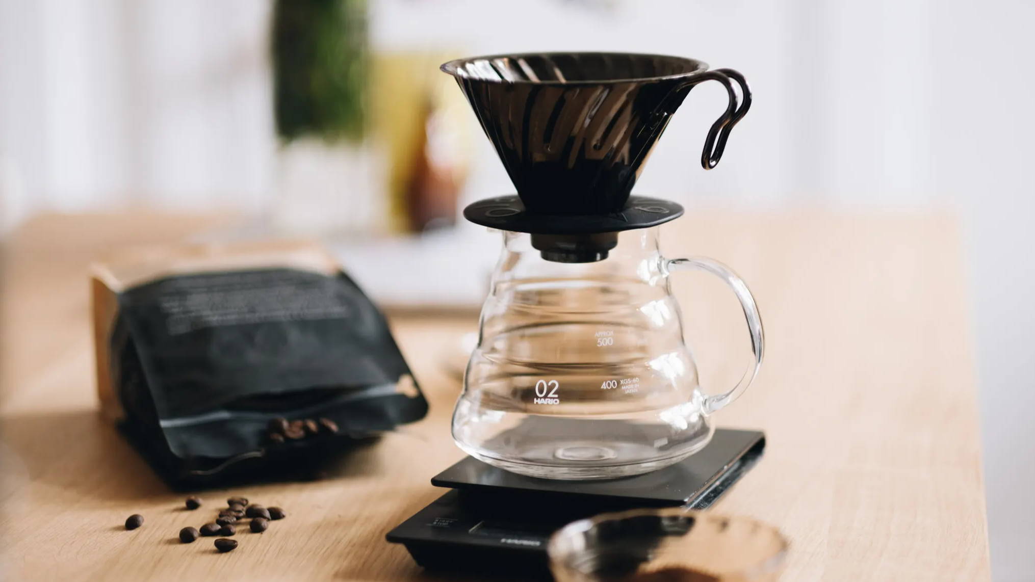  Hario decanter and Hario V60 brewer on a scale in a kitchen with a bag of coffee in the background