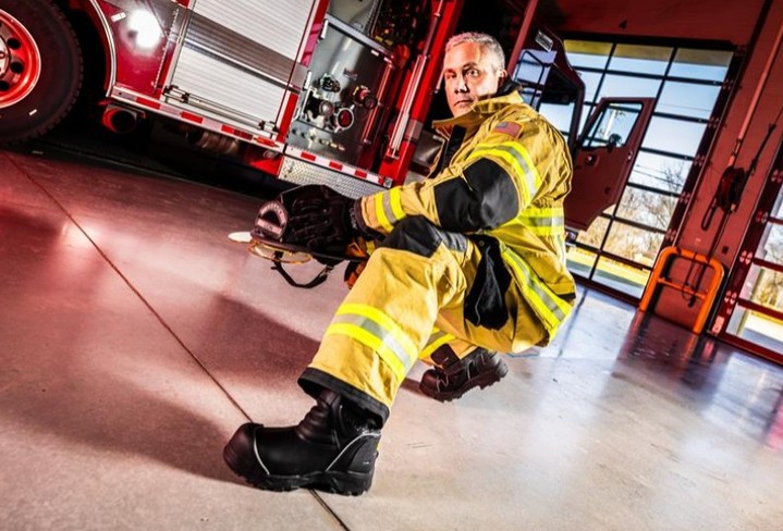 Firefighter in uniform preparing equipment in a fire station.