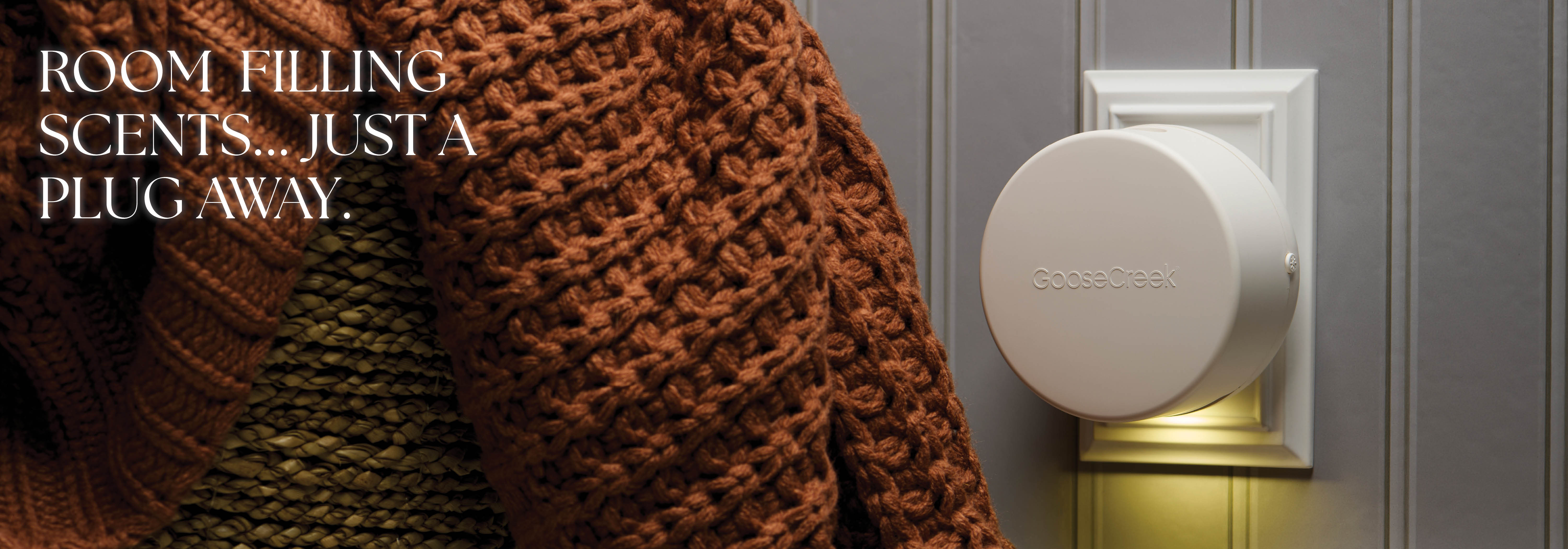 A person wearing a sweater next to a scent diffuser on the wall.