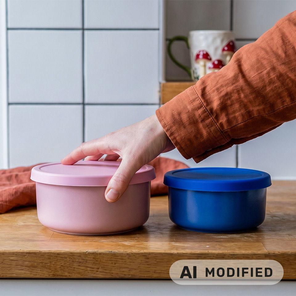 Une main tendue vers un récipient rose à côté d’un récipient bleu.