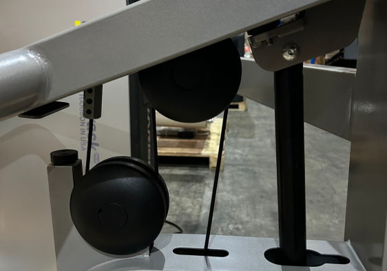 Black pulleys and cables on a machine in an industrial setting.