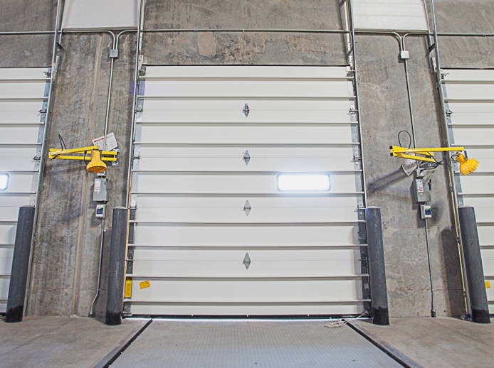 image of a loading dock with wall mounted dock lights, overhead dock door, and a dock leveler