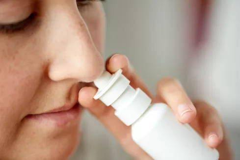 Een vrouw maakt gebruik van een neusspray