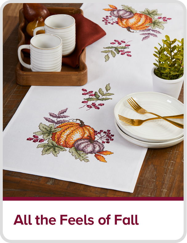 Table setting with fall-themed decor, including pumpkins and tableware. Text: All the feels of fall.