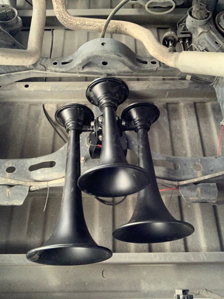 Three black air horns mounted to frame crossmember beneath truck bed