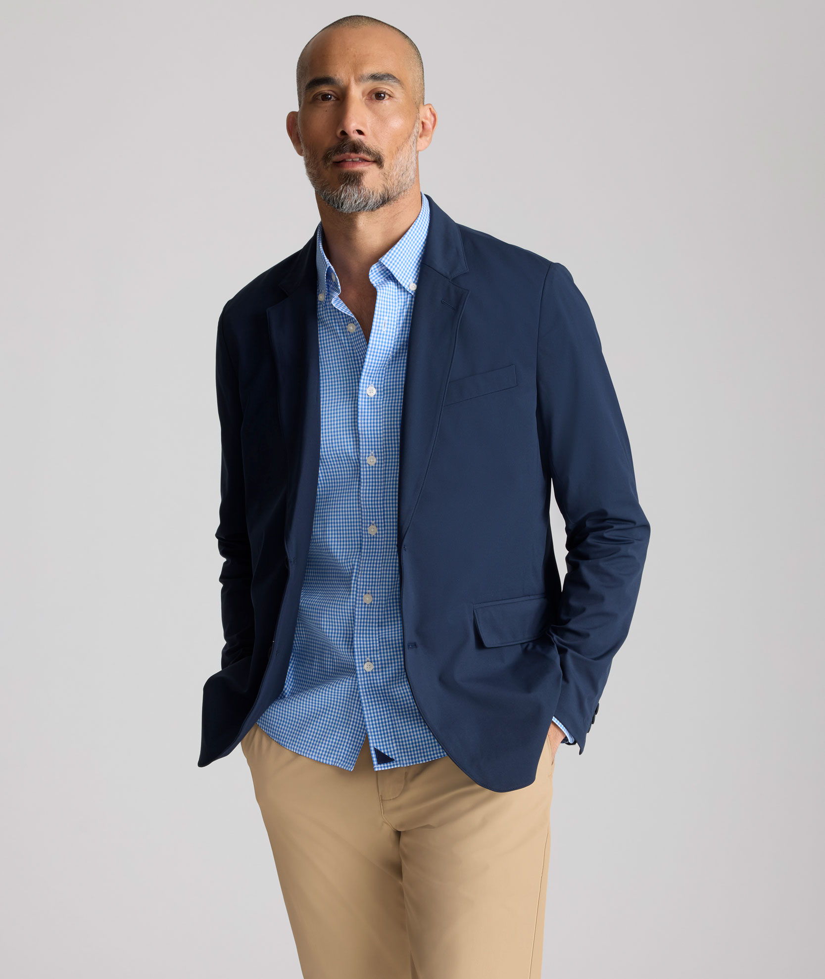 Man in a navy blazer and light blue shirt, standing confidently.